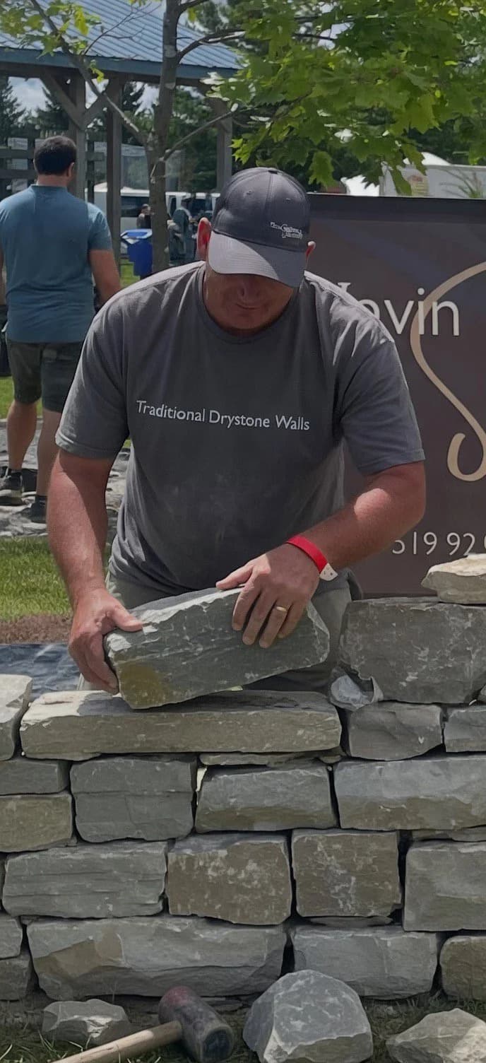 Kevin Hackson setting stone on a drystone wall in Southern Ontario